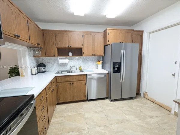 a kitchen with a sink a refrigerator a counter top space and cabinets