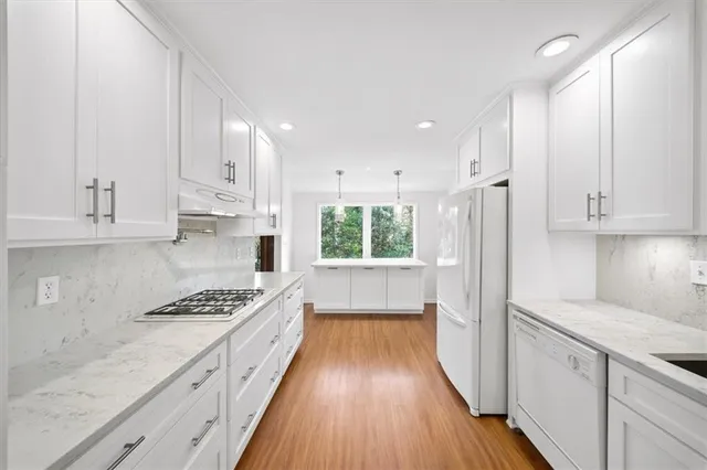 a kitchen with kitchen island white cabinets appliances and a window