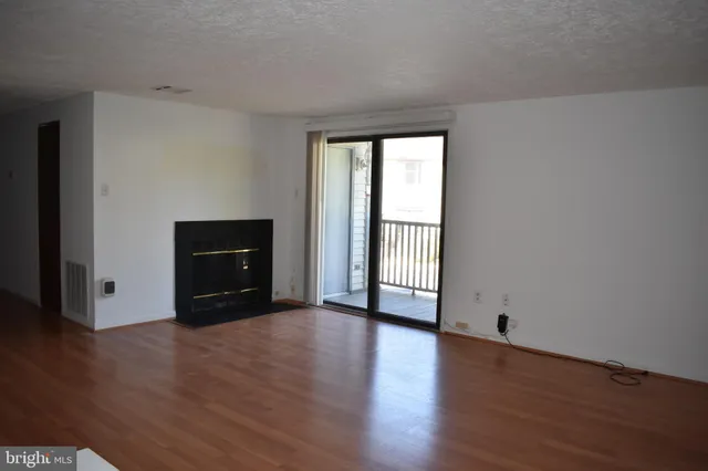 a big room with wooden floor and fireplace