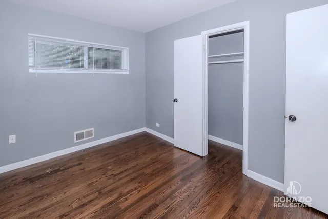 a view of an empty room with wooden floor and closet