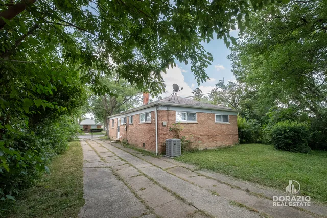 a view of a small house with a big yard and large trees