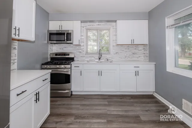 a kitchen with cabinets appliances a sink and a window