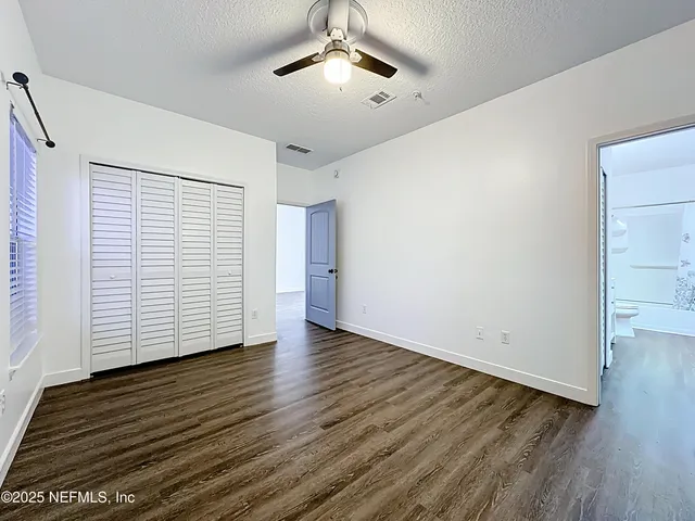 an empty room with wooden floor chandelier fan and windows