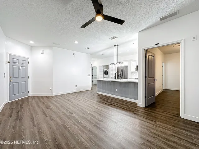 a view of kitchen and empty room with wooden floor