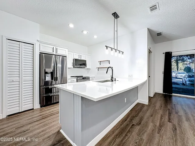 a kitchen with kitchen island a sink stainless steel appliances and wooden floor