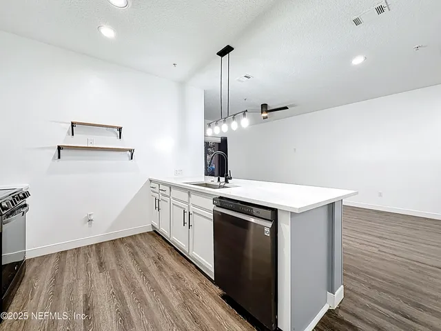 a kitchen that has a sink wooden floor and white stainless steel appliances