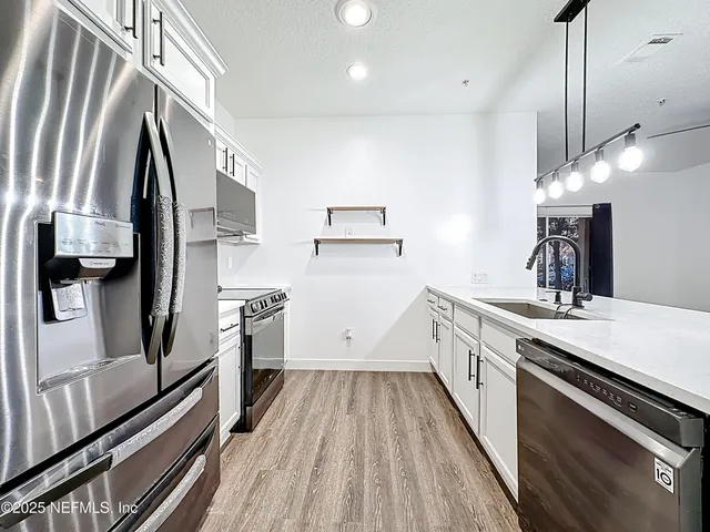 a kitchen with a sink appliances wooden floor and a counter top space