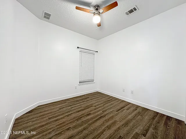 an empty room with wooden floor and ceiling fan