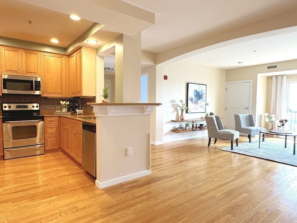 a kitchen with stainless steel appliances a stove a sink cabinets and wooden floor