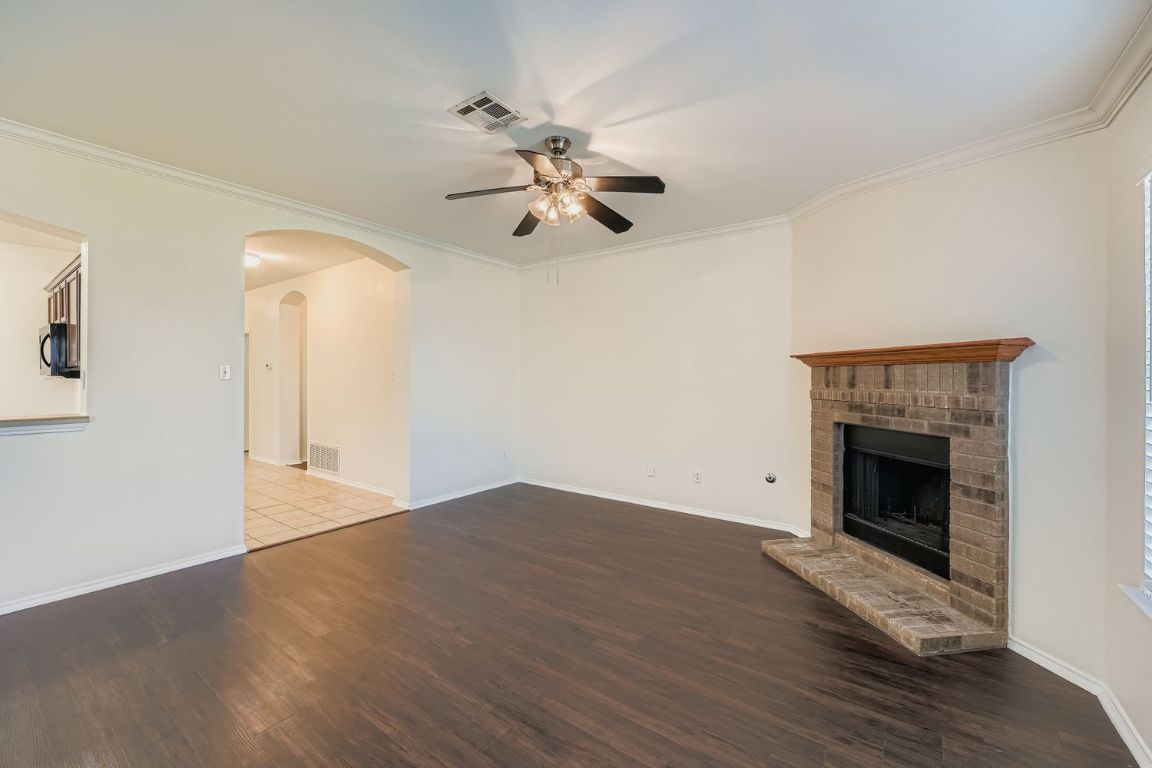 12612 Waynespur Lane Elgin, TX 78621 - Photo 4 of 22 an empty room with a fireplace and wooden floor