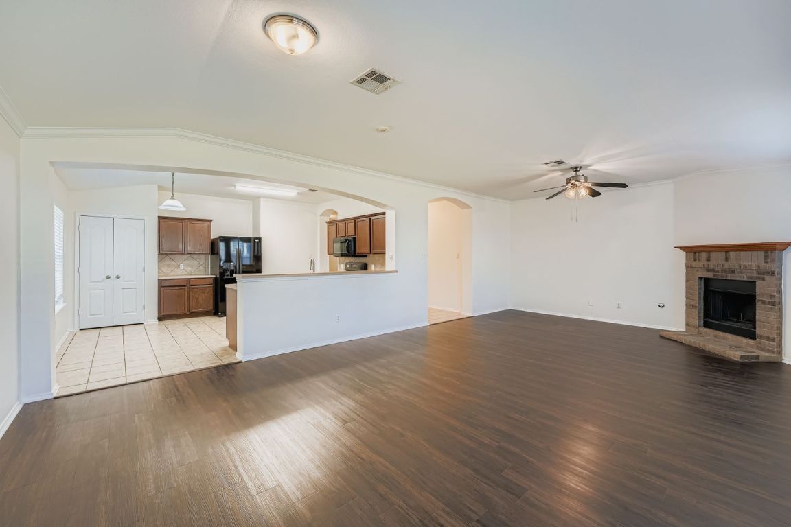 12612 Waynespur Lane Elgin, TX 78621 - Photo 7 of 22 a view of empty room with wooden floor and kitchen