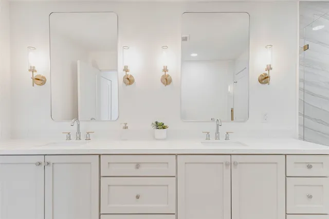 a spacious bathroom with a double vanity sink a mirror and a shower