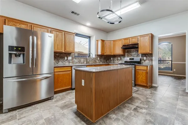 a kitchen with stainless steel appliances granite countertop a refrigerator a stove a sink a center island and a window