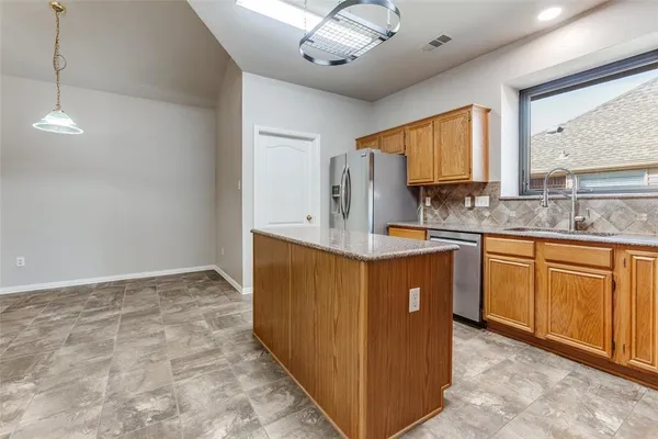 a kitchen with kitchen island granite countertop a sink stainless steel appliances cabinets and a counter top space