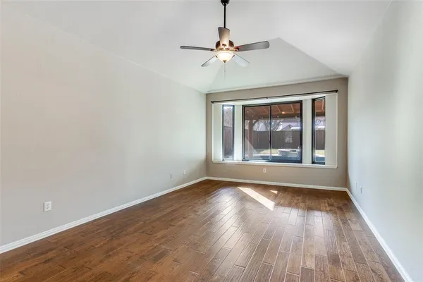 a view of an empty room with wooden floor fireplace and a window
