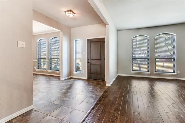 a view of an empty room with glass door and wooden floor