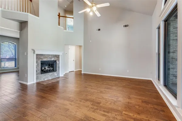 an empty room with wooden floor fireplace and windows