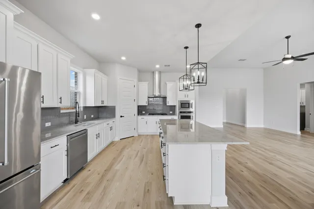 a kitchen with kitchen island a counter top space wooden floor and stainless steel appliances