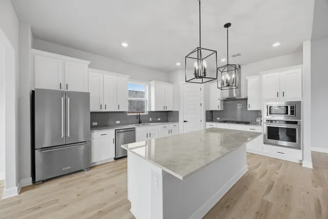 a kitchen with stainless steel appliances granite countertop a sink stove and refrigerator