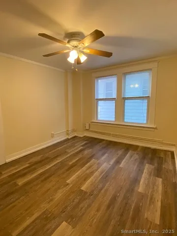 a view of an empty room with window and chandelier fan