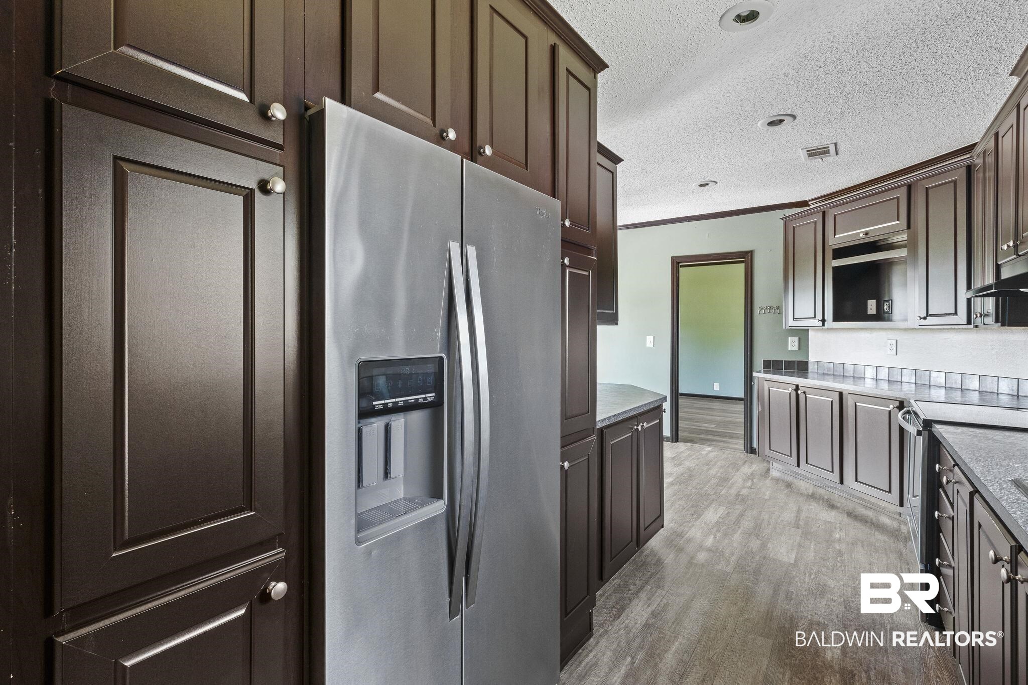 6870 Cecilia Court Theodore, AL 36582 - Photo 25 of 83 Kitchen with dark brown cabinetry, appliances with stainless steel finishes, light wood-type flooring, and ornamental molding