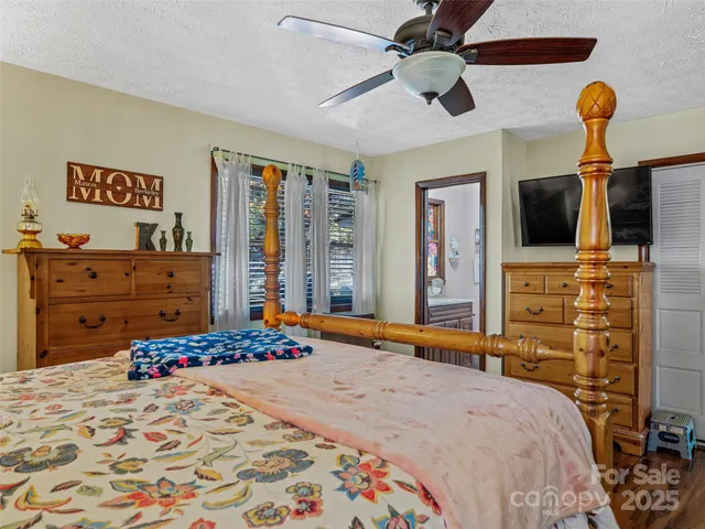 a bedroom with a bed and a flat tv screen on dresser