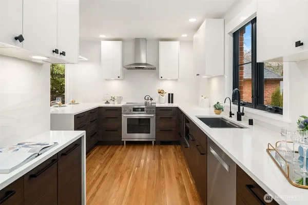 a kitchen with stainless steel appliances a sink dishwasher a stove top oven a refrigerator with wooden floors