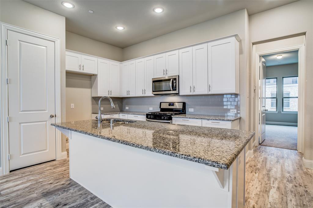 a kitchen with granite countertop a sink a counter top space stainless steel appliances and cabinets
