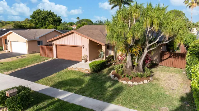 a view of a white house with a big yard and potted plants