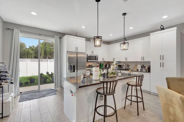a kitchen with kitchen island a large counter top space appliances and a chandelier