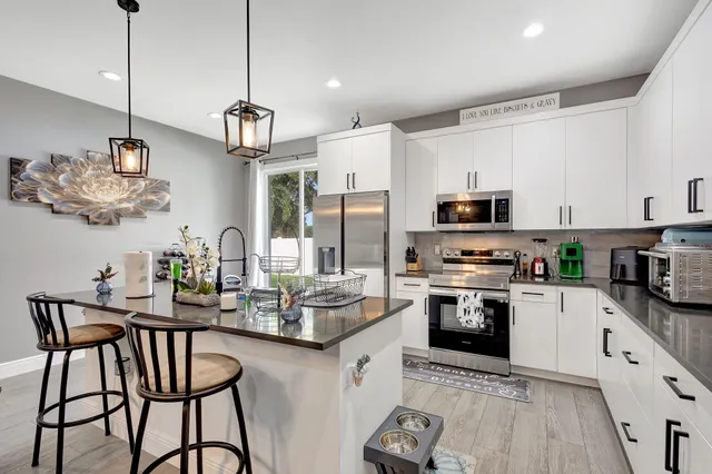 a kitchen with stainless steel appliances granite countertop a sink a stove a dining table and chairs with wooden floor