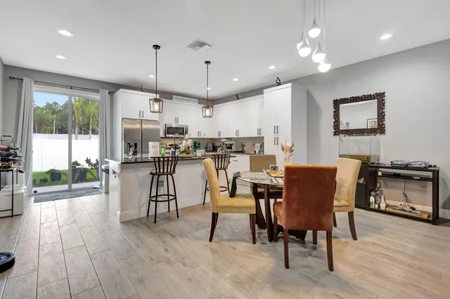 a dining room with stainless steel appliances kitchen island granite countertop a table chairs and a refrigerator
