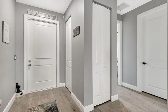 a view of a hallway with wooden floor and closet area