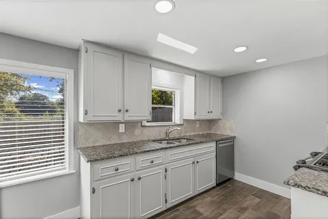 a kitchen with granite countertop cabinets sink and window