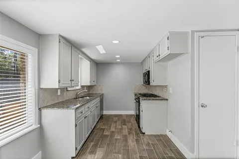 a kitchen with granite countertop a sink and a stove top oven
