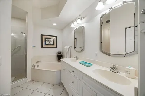 a bathroom with a tub a double vanity sink and mirror