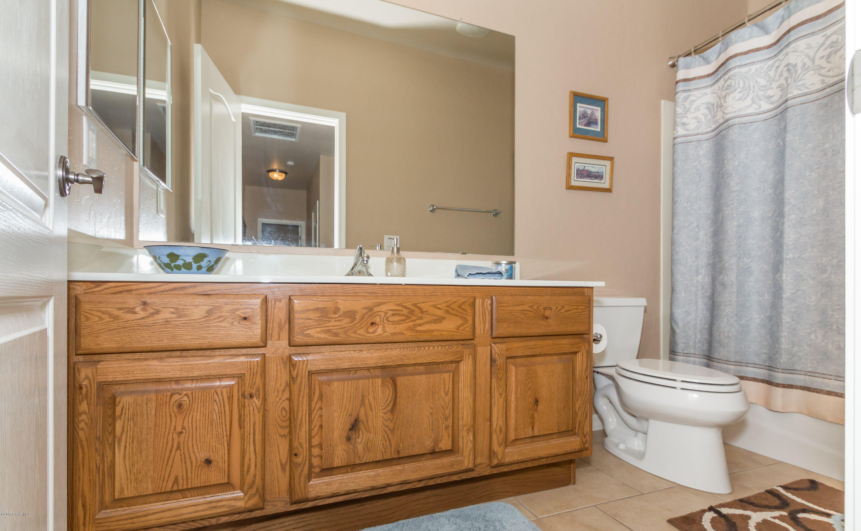 1197 Rusty Nail Road Prescott Valley, AZ 86314 - Photo 12 of 40 a bathroom with a sink a toilet a mirror and shower curtain