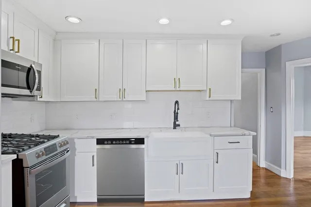 a kitchen with stainless steel appliances granite countertop white cabinets and a stove top oven