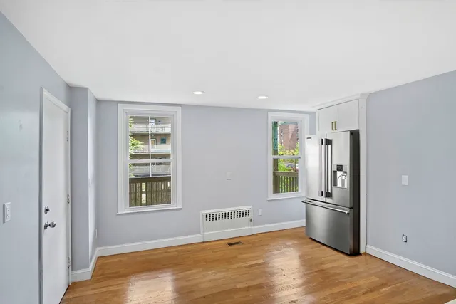 a view of an empty room with a window and wooden floor