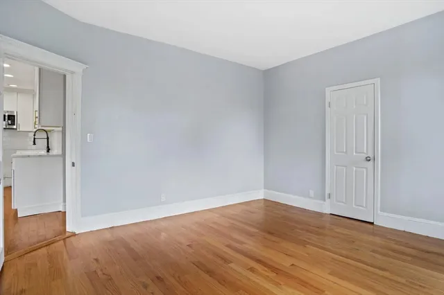 a view of an empty room with wooden floor and a bathroom