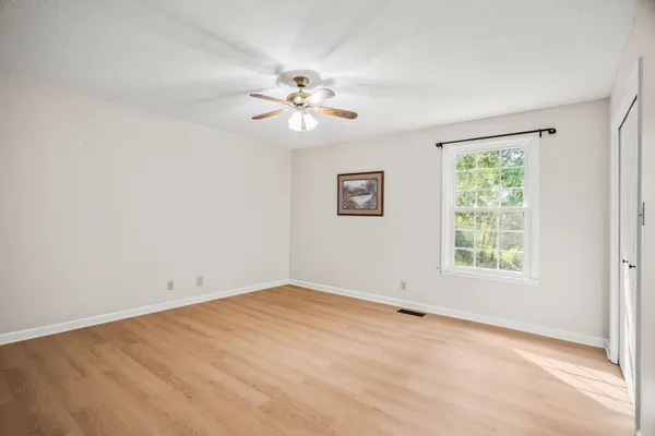 an empty room with windows and fan