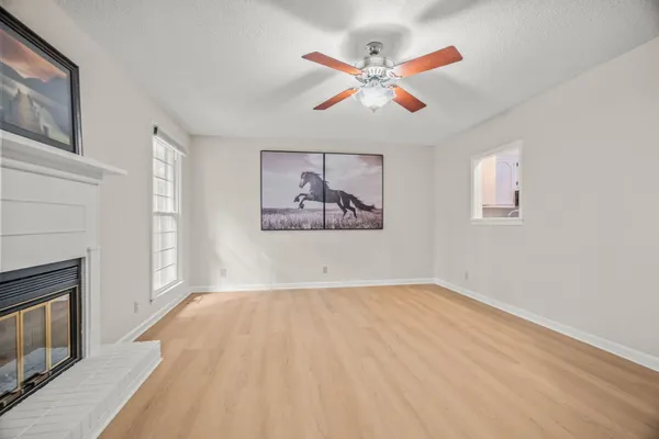 a view of a livingroom with wooden floor a ceiling fan and a window