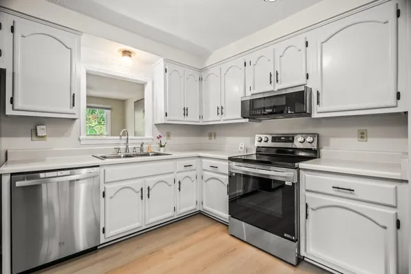 a kitchen with white cabinets stainless steel appliances and sink