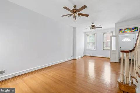 a view of an empty room with a window and wooden floor