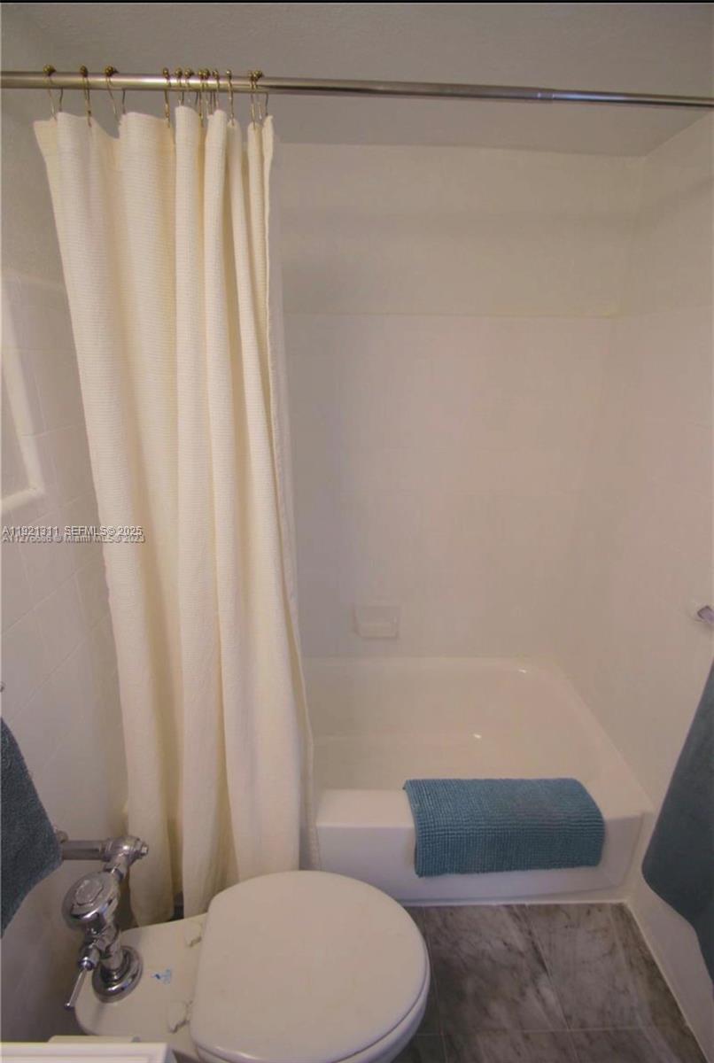 1500 Bay Road, Unit 374S Miami Beach, FL 33139 - Photo 20 of 33 a bathroom with a toilet and a shower curtain