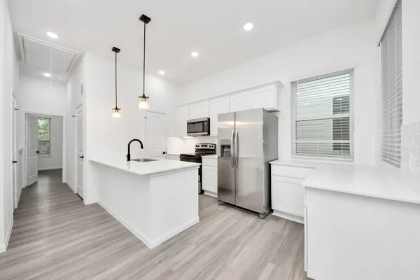 a large kitchen with white cabinets stainless steel appliances