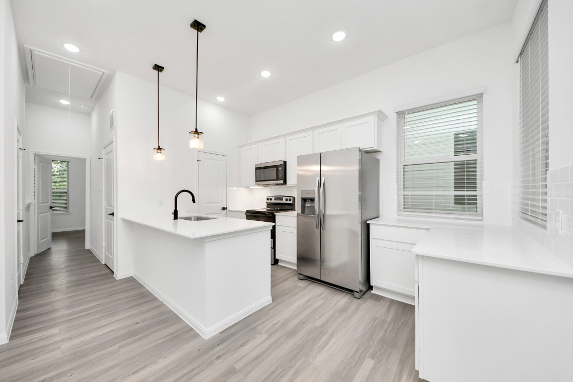 a large kitchen with white cabinets stainless steel appliances