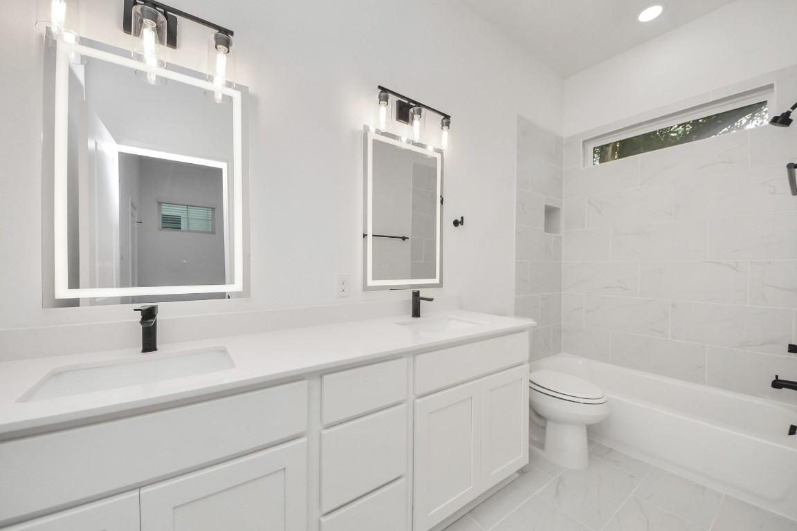 5103 Mallow Street, Unit B Houston, TX 77033 - Photo 19 of 30 a bathroom with a double vanity sink toilet mirror and bathtub
