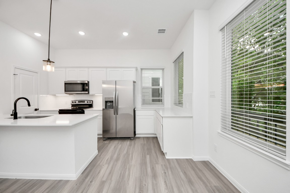 5103 Mallow Street, Unit B Houston, TX 77033 - Photo 3 of 30 a kitchen with stainless steel appliances a refrigerator sink and wooden floor