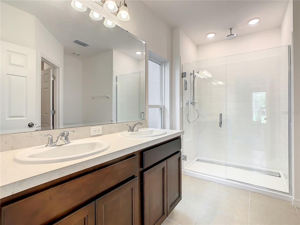 1761 Tree Shade Drive Davenport, FL 33837 - Photo 13 of 20 a bathroom with a double vanity sink mirror double and shower
